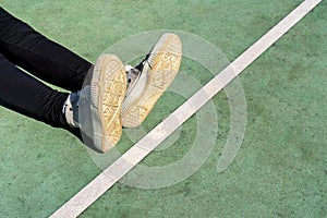 Girl legs in sneakers on green rubberized sport ground background