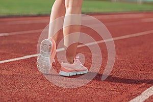 Girl legs in sport shoes standing on a running track with stadium stands. back view. close up