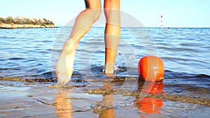 Girl legs step over washed up buoy and go into sea closeup