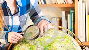 Girl in library with globe and magnifying glass