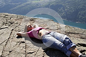 Girl lie on fjord cliff edge