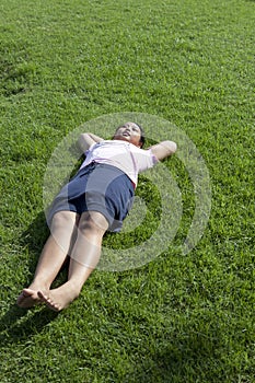 Girl lied on green grass field wiht morning light