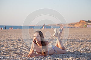 Girl lies on the Beach talking phone