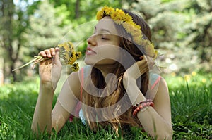 He girl lies on the grass with a wreath of wild flowers on her h