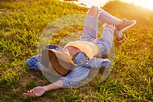 Girl lies on green grass near the river on a summer sunny day