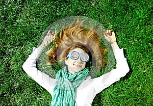 Girl lies at green grass at the park.