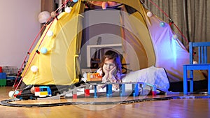 girl lies in her tent and plays railroad, starts the train. cozy children's game