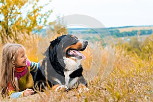 girl lies next to big dog on autumn walk