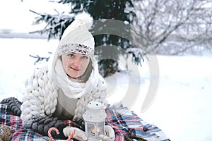 The girl lies on the snow in the winter forest or park. Concept - Christmas vacations and holidays.