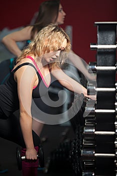 Girl lifts dumbbell with an effort