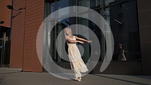 Girl in a light dress dancing in the open air. Ballerina is spinning on tiptoe and jumping high