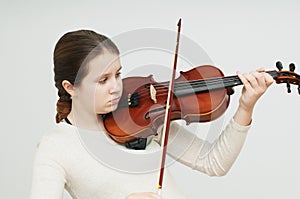 A girl in light dress looking at the srings playing the violin over white background