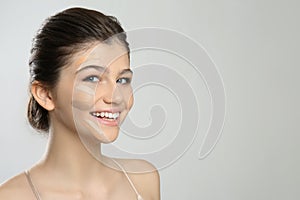 Beautiful girl on light grey background. Using concealers and foundation for face contouring photo