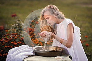 Girl in a linen dress scooped up water to wash