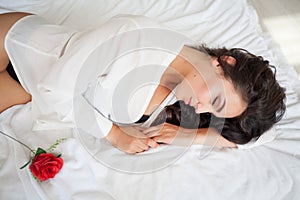 Girl in lingerie lying on a bed with a rose