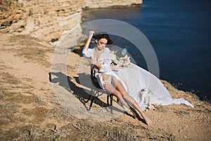 Girl in lingerie on top of a mountain overlooking the ocean. Charges of the bride, bride`s morning.