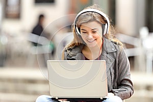 Girl listening and downloading music from laptop