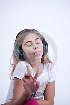 Girl listening a music on headphone Making a sign of peace and love