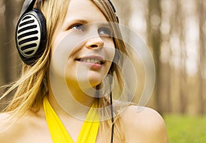 Girl listening music in headphones. Spring nature