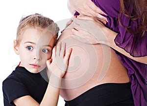 A girl is listening to the abdomen of her mother