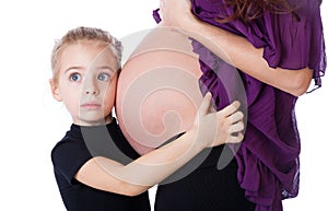 A girl is listening to the abdomen of her mother