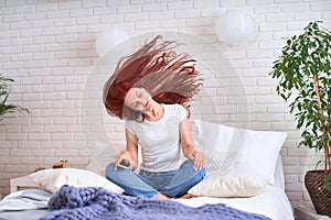 Girl listening to music in headphones on the bed. red-haired young beautiful girl in jeans and t-shirt happy in headphones