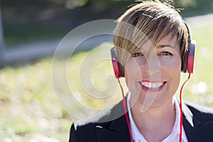 Girl listening to the music with headphones in a park