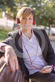 Girl listening to the music with headphones in a park