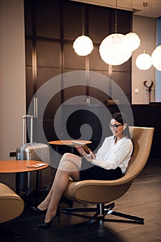 Girl listening to music through headphones on the tablet at business lounge at the airport.