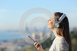 Girl listening to music holding phone in city outskirts photo