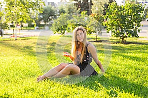 Girl listening to music streaming with headphones in summer on a meadow.