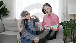 Girl listening to music by using headphone while mom playing ukulele. Pedagogy.