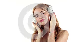 Girl listens to her favorite music through headphones. White background. Slow motion