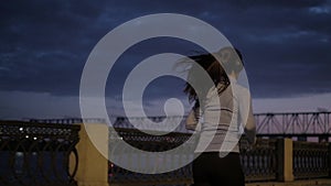 Girl listens to music with headphones while Jogging in the city at night. sportswoman in sportswear on background of the