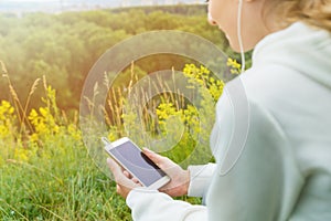 A girl listens to music with headphones in nature