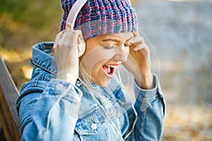 Girl listens to music in headphones. Smiling girl relaxing, music a smartphone and headphones. Outdoors portrait of a