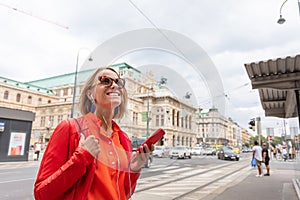 A girl listens to music from her phone on the streets of Vienna and against the background of the opera house, Austria