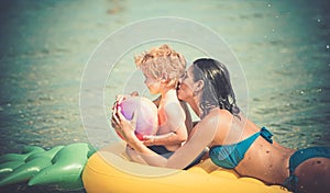 Girl with little boy kid swim on yellow air mattress in the water in the summer