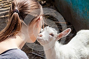 The girl and the little goat look at each other with tenderness