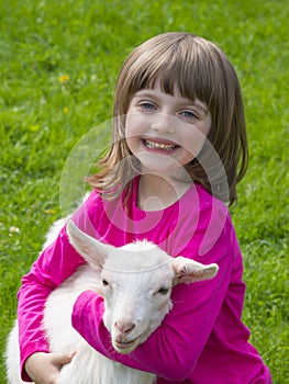 Girl and little goat sitting on a meadow