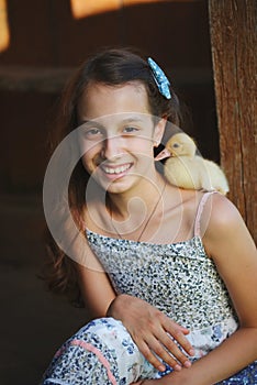 Girl with little yellow duckling in summer village