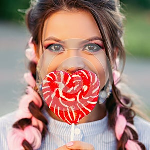 Girl with lollipop. Beauty Glamour Model woman with trendy hair holding pink sweet colorful lollipop candy