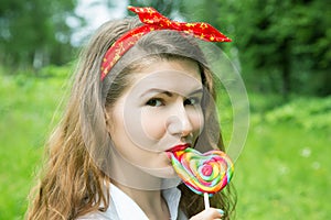 Girl with a lollipop in the trees in the summer