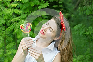 Girl with a lollipop in the trees in the summer