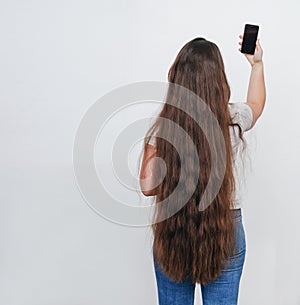 Girl with long beautiful hair takes a selfie, turned her back on the camera