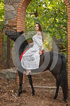 A girl with long black hair riding a horse.