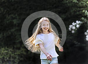 Girl with long blond hair dances in the garden on a beautiful spring day and is cheerful
