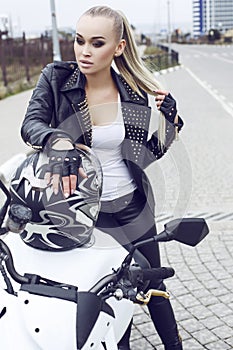 girl with long blond hair in leather jacket,posing on motorbike