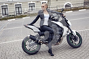 girl with long blond hair in leather jacket,posing on motorbike