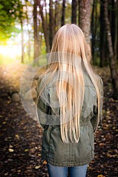 Girl with long blonde hair from behind outside in the forest
